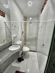 uma casa de banho com um WC e uma cabina de duche em vidro. em Hotel Sol e Mar em Vitória