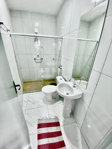 a white bathroom with a sink and a toilet at Hotel Sol e Mar in Vitória