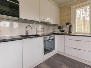 uma cozinha com armários brancos, um lavatório e uma janela em Holiday Home Miilu by Interhome em Jyrkkä