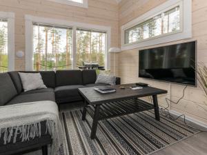 a living room with a couch and a table and a tv at Holiday Home Miilu by Interhome in Jyrkkä