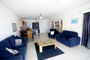 a living room with blue couches and a table at Pissouri Beach Apartments in Pissouri