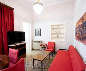 een woonkamer met een rode bank en een tv bij Best House, Marina Home, Athens Avenue, Patra in Patra
