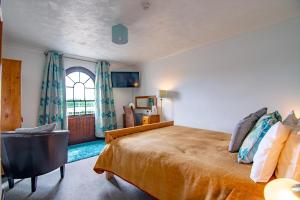 um quarto com uma cama, uma cadeira e uma janela em The Station Guest House em Woodbridge