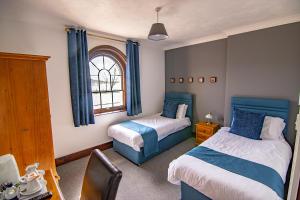 een slaapkamer met 2 bedden en een raam bij The Station Guest House in Woodbridge