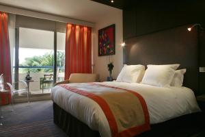 a bedroom with a large bed and a balcony at Hôtel & Spa Vatel in Nîmes