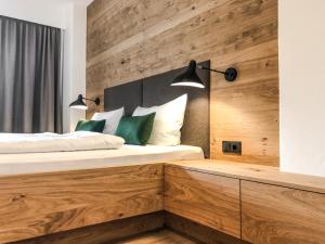 a bedroom with a bed with a wooden wall at ride & relax Aparthotel Schwarz in Eben im Pongau