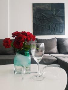 a table with a vase with red roses and a wine glass at Apartment IRIS in Novi Sad