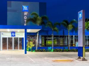 a blue building with palm trees in front of it at ibis budget Sertaozinho in Sertãozinho