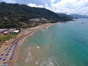 Corfu Resorts Villas في بيليكاس: اطلالة جوية على شاطئ فيه مظلات والمحيط