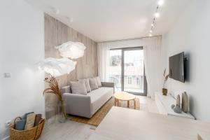 a white living room with a couch and a tv at Apartment Balticus 19A by Renters in Międzyzdroje