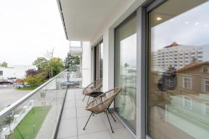 a balcony with two chairs and glass doors at Apartment Balticus 19A by Renters in Międzyzdroje