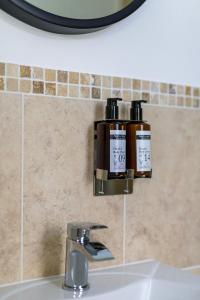 lavamanos en el baño con 2 botellas de jabón en la pared en The Garden House B&B en Bristol