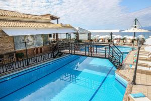 a pool at a resort with tables and umbrellas at Navigator Villas - Houses in Acharavi