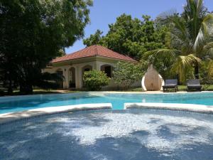 a swimming pool in front of a house at Safina Cottages in Diani Beach