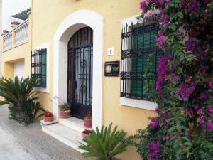 un edificio amarillo con una puerta negra y flores púrpuras en Joanet Guarda turismo familiar en plena naturaleza en La Guardiola