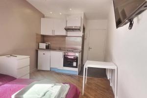 a small kitchen with white cabinets and a table in it at Rouen hyper centre ville Palais de Justice in Rouen