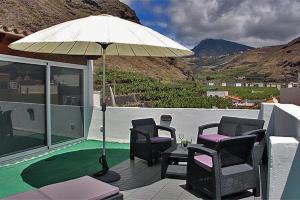 eine Gruppe Stühle und ein Sonnenschirm auf einer Terrasse in der Unterkunft VV ATICO PUERTO TAZACORTE in Puerto