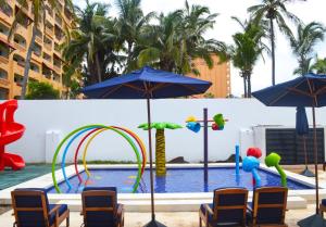 una piscina con sillas y sombrillas junto a una piscina en The Inn at Mazatlan, en Mazatlán