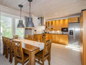 Il dispose d'une cuisine avec une table en bois, des chaises et un réfrigérateur. dans l'établissement Holiday Home Villa valo by Interhome, à Kolinkylä
