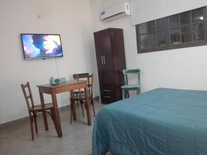 1 dormitorio con cama, mesa y TV en MONOambienteporDIA en Bahía Blanca