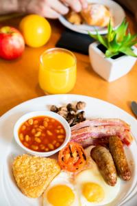 un piatto bianco di prodotti per la colazione con salsiccia e fagioli di Holiday Inn Cardiff City, an IHG Hotel a Cardiff