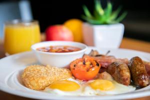 a plate of breakfast food with eggs sausage and tomatoes at Holiday Inn Cardiff City, an IHG Hotel in Cardiff