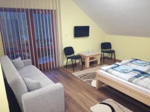 a living room with a bed and a couch at Kaptárlevegős Vendégház in Füzesgyarmat