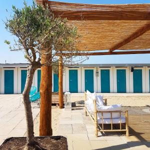 un patio con sedie e un albero di fronte a un edificio di Alba Hotel a Marina di Ravenna