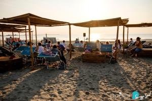 um grupo de pessoas sentadas em cadeiras na praia em Alba Hotel em Marina di Ravenna