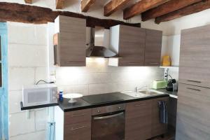 a kitchen with wooden cabinets and a sink and a microwave at Le Refuge des Elfes in Bourré