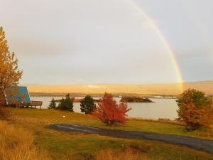 a rainbow over a lake with a bench on a hill at Ormurinn Cottages in Egilsstadir