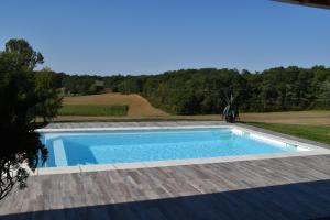 a swimming pool in a yard with a wooden deck at Le Refuge des Épicuriens in Eymet