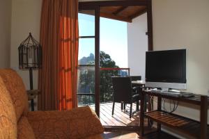 a living room with a television and a desk with a computer at VACACIONAL LA TEA THE BEST LOCATION and THE BEST VIEWS in Tejeda