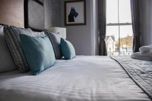 a bed with a white comforter and pillows at The Portree Hotel in Portree
