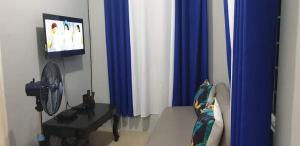 a living room with blue and white curtains and a tv at Apple Transient House in Angeles