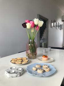 una mesa con un jarrón de flores y platos de golosinas en Chambre d 'hôtes Chez Manon et Hugo, en Béthune