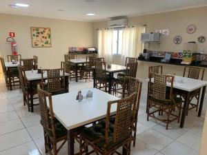 a dining room with white tables and chairs at Hotel e Pousada Areia da Praia in São Vicente