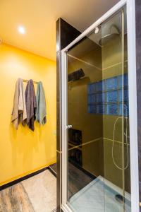 baño con cabina de ducha de cristal y paredes amarillas en GRAND STUDIO ENTRE MER ET MONTAGNE, en Le Bar-sur-Loup
