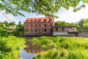 an old brick building next to a body of water at Nostalgia Poganice in Potęgowo