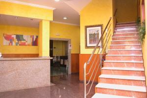 un vestíbulo con escaleras en un edificio con paredes amarillas en Hotel El Puente, en Sanxenxo