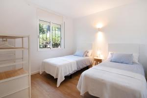 2 camas en una habitación blanca con ventana en Casa OSONA con jardin cerca de la Playa, en Tarragona