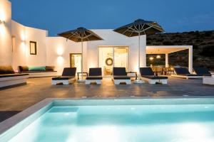 a swimming pool with chairs and umbrellas on a patio at PAROS VILLA BLUE SENSES in Aliki