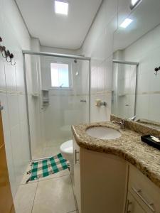 a bathroom with a shower and a sink and a toilet at Excelente apt para veraneio c Wi-Fi tv e box in Capão da Canoa