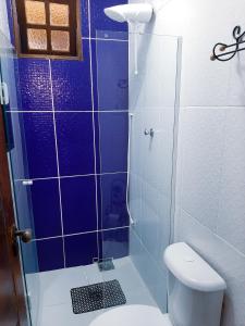 a bathroom with a toilet and a glass shower at Suites Oliveira in Arraial do Cabo