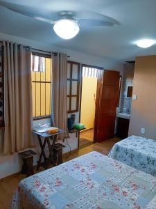 a bedroom with two beds and a table and windows at Suites Oliveira in Arraial do Cabo