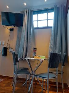 a table and two chairs in a room with a window at Suites Oliveira in Arraial do Cabo