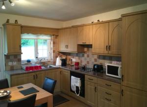 a kitchen with wooden cabinets and a table and a microwave at Glenrandel Valley in Claudy