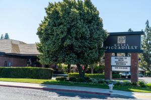 un panneau devant un bâtiment avec un arbre dans l'établissement Hotel Piccadilly, à Fresno