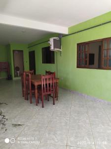 a dining room with green walls and a wooden table and chairs at Chalés Margarida in Ubatuba