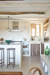 a kitchen with white counters and bar stools at Luxury townhouse in the heart of medieval St Paul de Vence in Saint-Paul-de-Vence